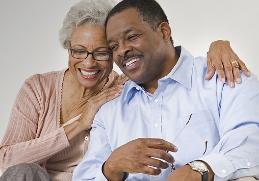 An elderly couple smile together after talking about their retirement plan.