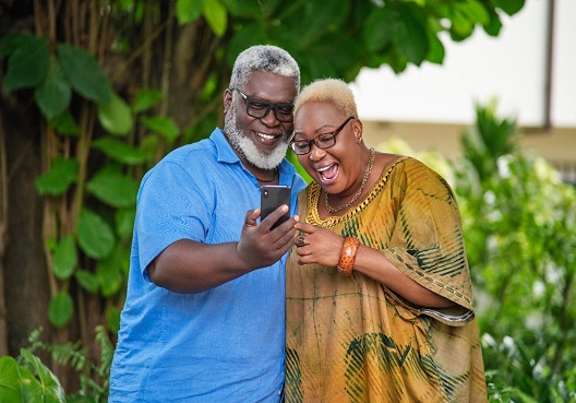 An older couple take a photo while enjoying a comfortable retirement because of their annuity. An elderly couple spend their retirement together and take a photo outdoors.