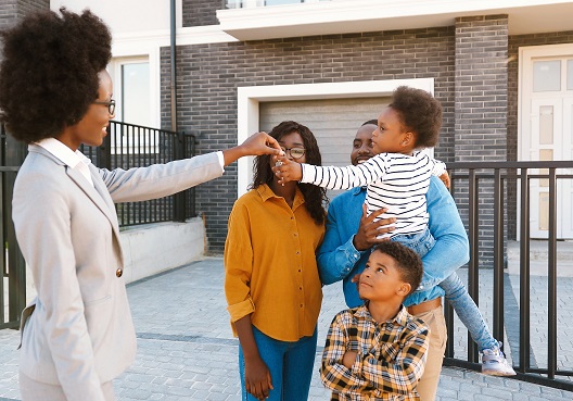 A family accept the keys to their new home, covered by the Mortgage Protection Plan. A Ghanaian family with two children accept keys for their new home from their real estate agent.