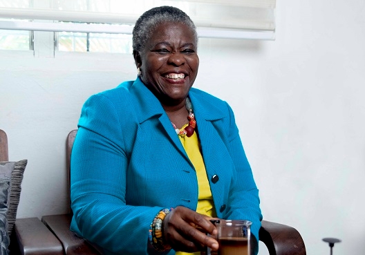 An older woman smiles as she sits on a chair, knowing that she has enough savings for retirement. An elderly woman sits and enjoys a cup of tea.