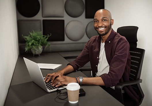 A man sitting in his home office working on his laptop