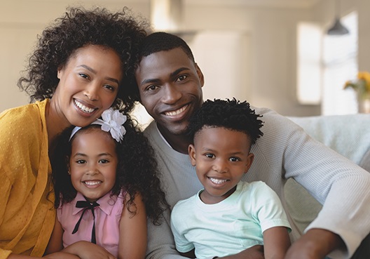 A family relaxes at home, resting easy knowing their futures are protected through life assurance. A Ghanaian couple with two children enjoy spending time together at their home.