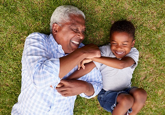 An elderly man spends time with his grandson, resting easy knowing his future is provided for. A grandfather plays with his grandchild and enjoys spending time with him outdoors.